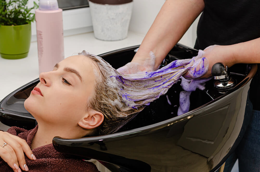 Hair Stylist Applying Coloring Purple Shampoo