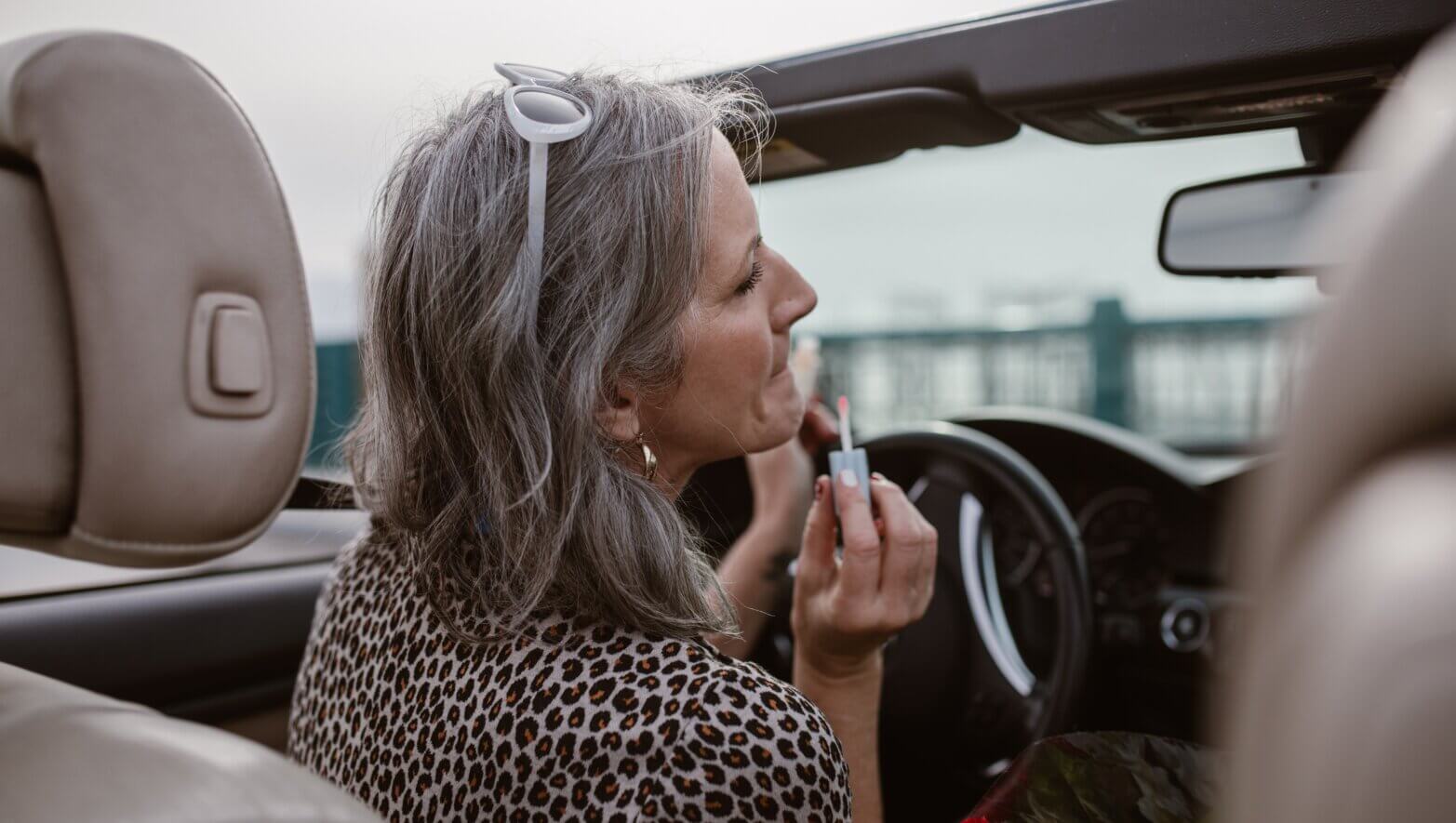 Image of woman putting on a lipstick