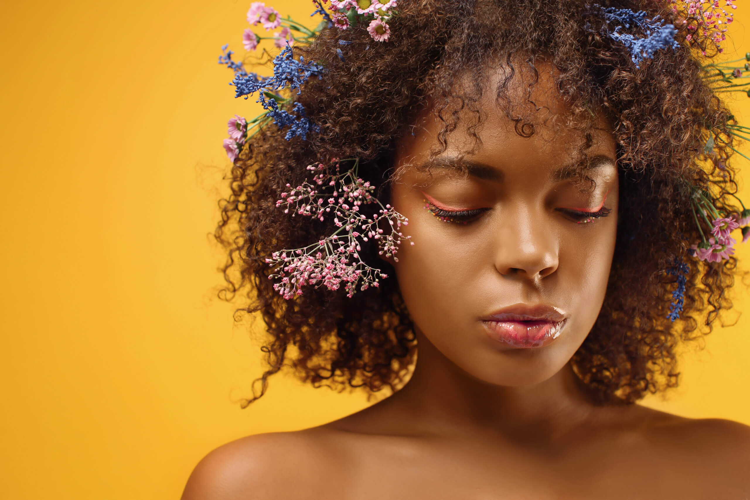 Image of a beautiful young African-American woman with flowers in hair against color background