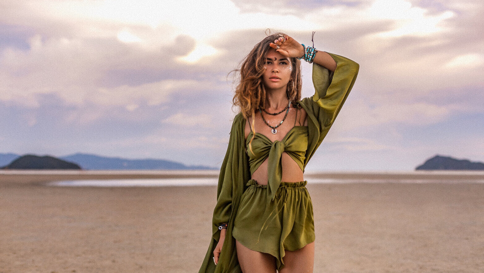 Image of a beautiful young woman in stylish costume on the beach at sunset