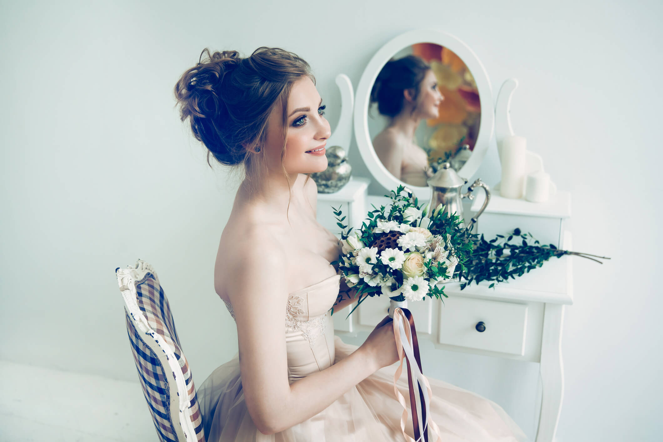 Image of a bride with styled hair and holding a bouquet 