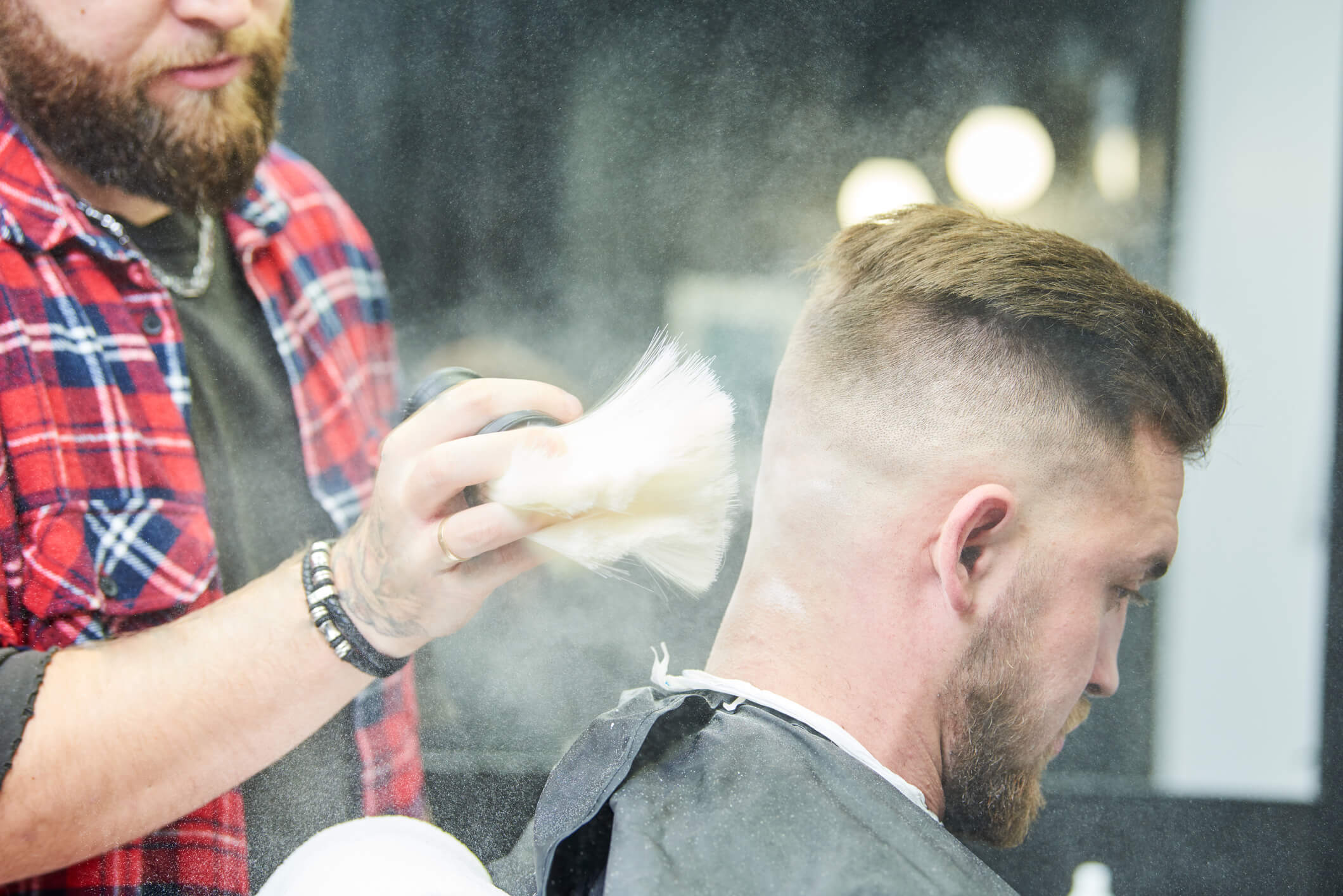 Image of a barber using and applying talc to client