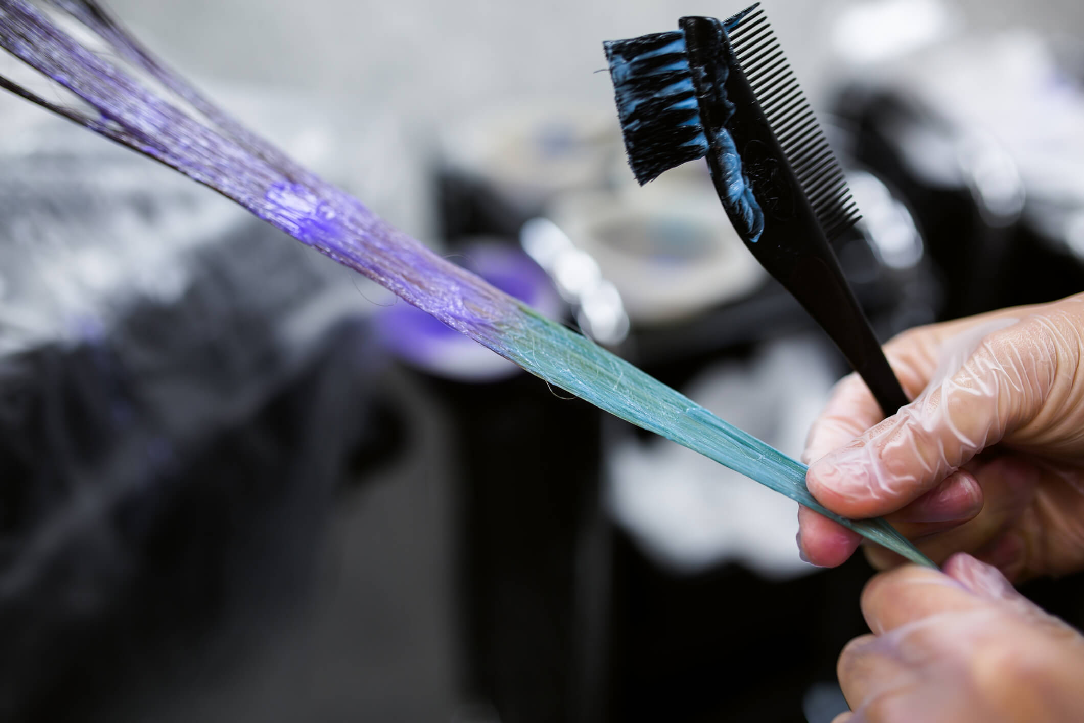 Image of a stylist with gloves dying long blue and purple hair