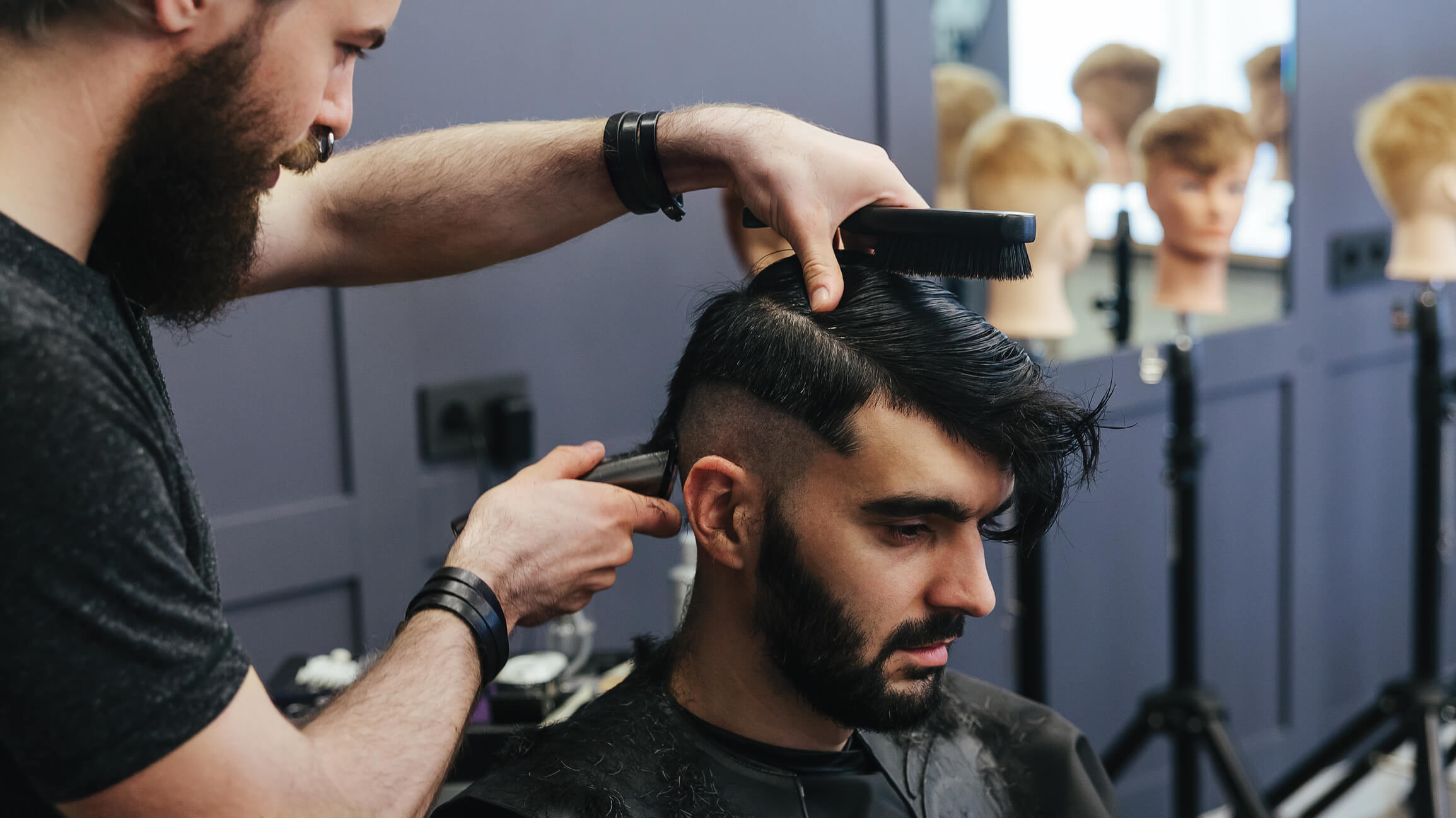 Image of a male barber combing and shaving hair of male client