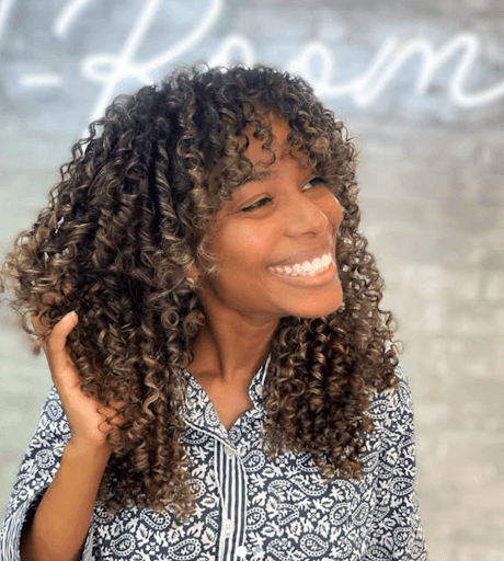 happy woman with beautiful curly hair in salon