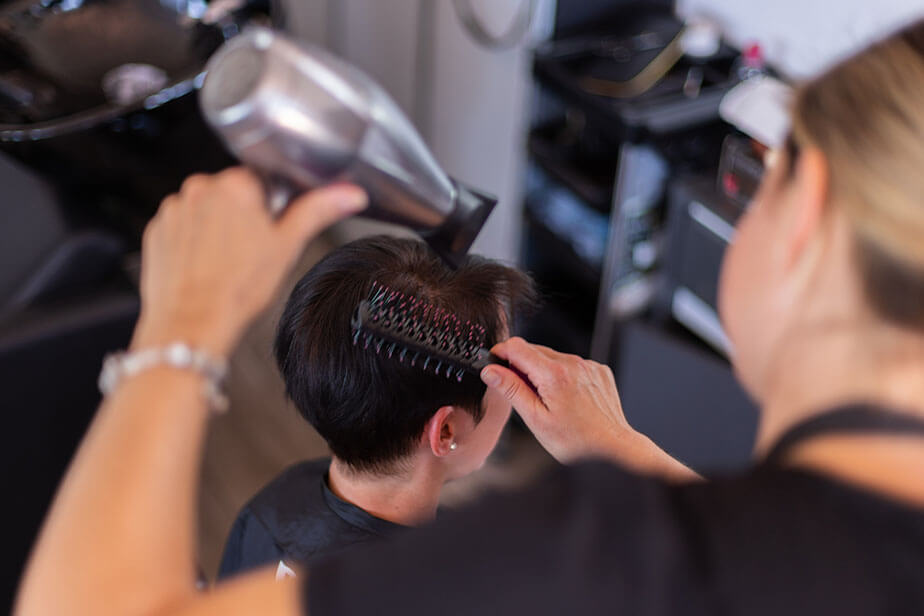 hairstylist blow drying client hair