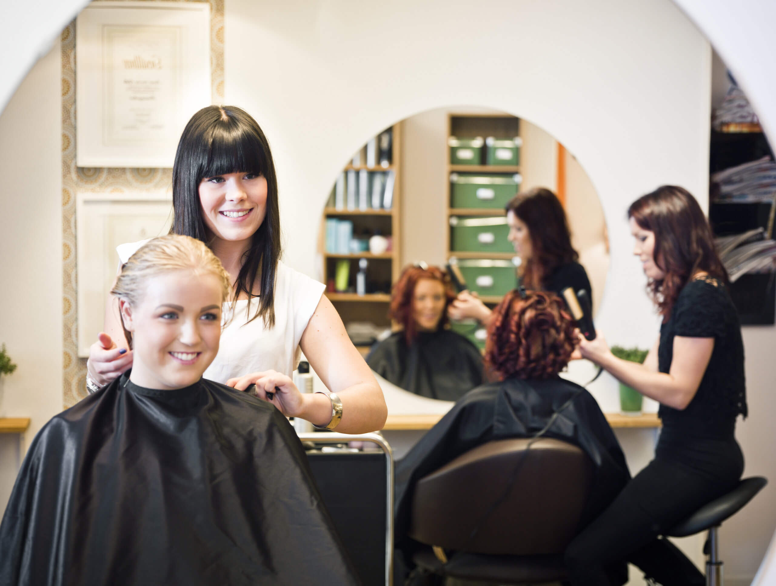 Salon Stylist catering to her blonde customer looking at a mirror