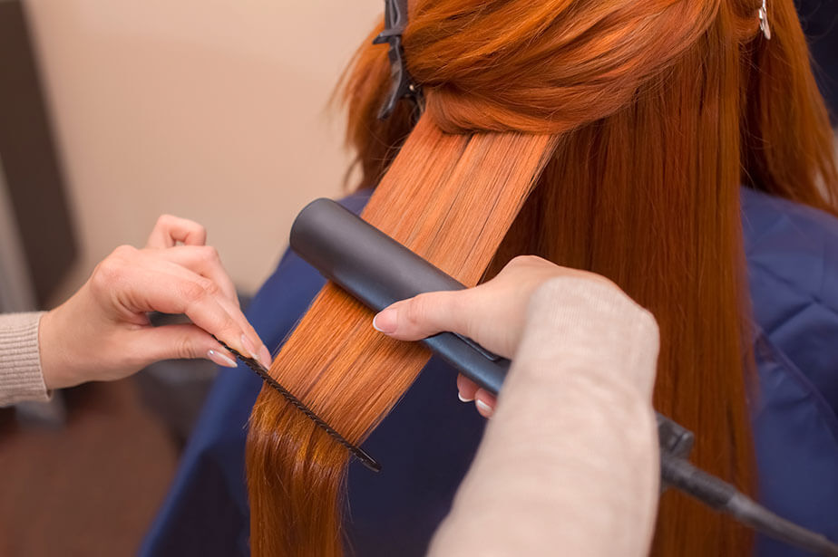 stylist straightening client hair