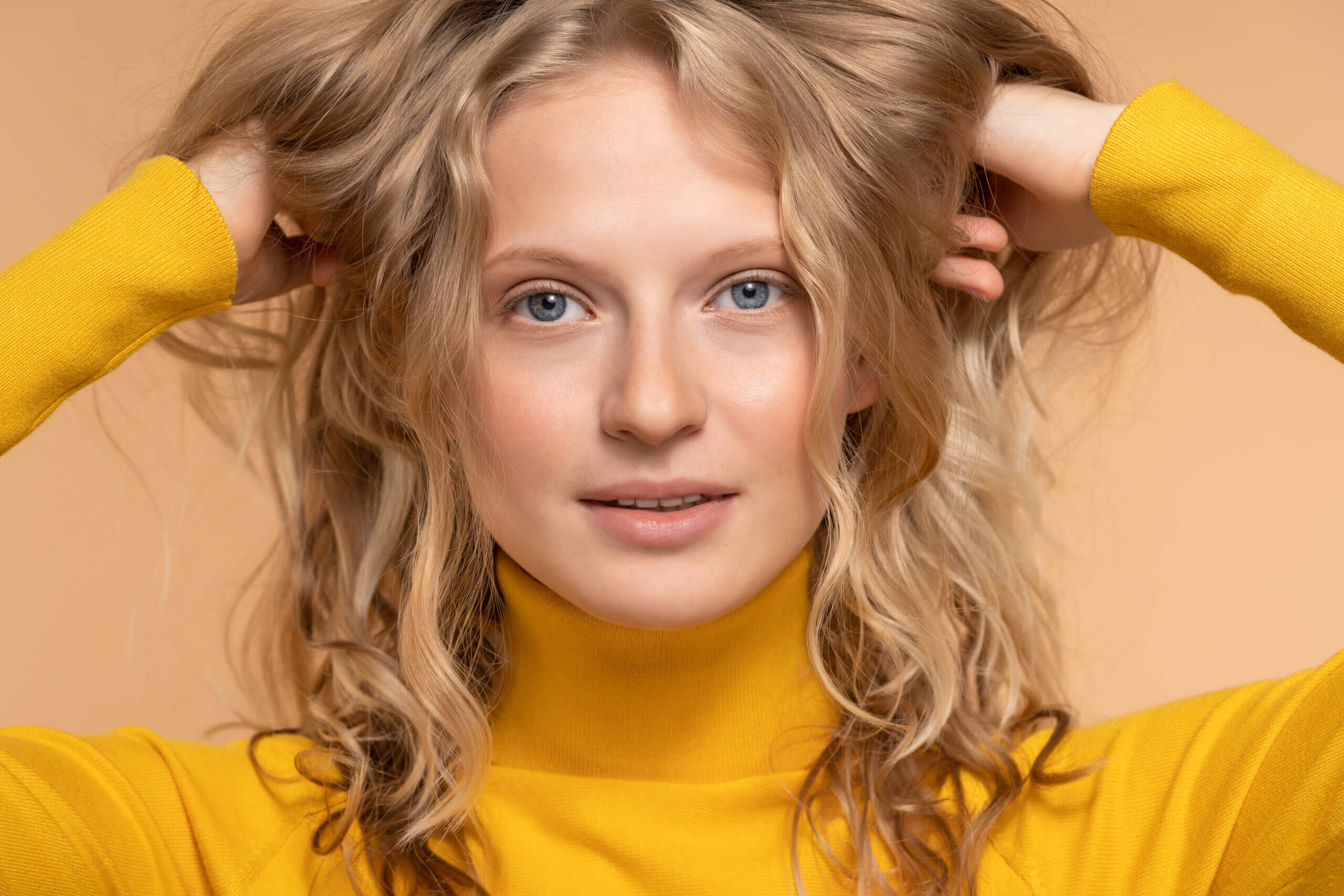 young-blonde-woman-fresh-skin-touching-her-natural-soft-curly-hair-looking-camera-has-no-makeup-wear-yellow-closeup