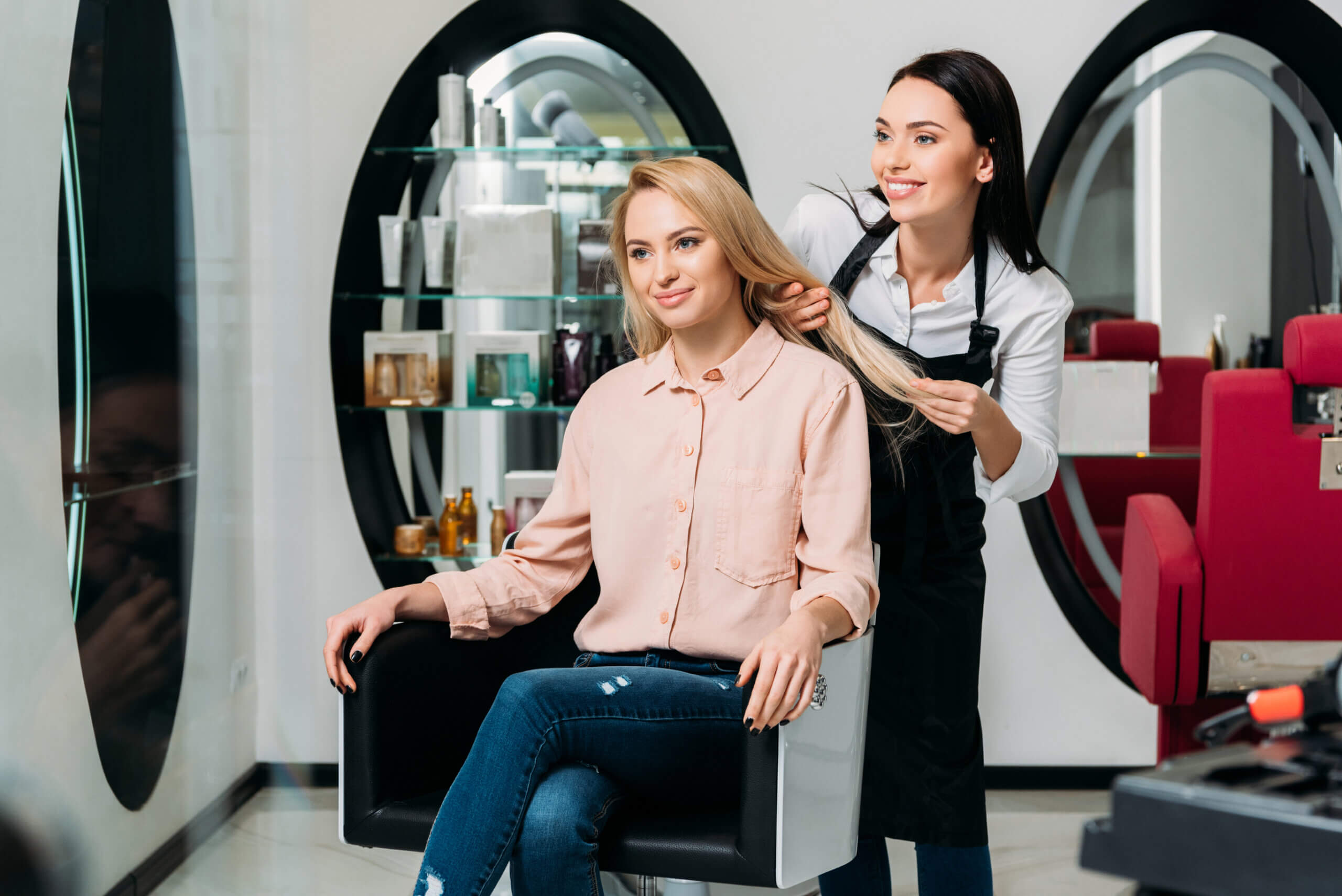 Happy hairdresser and customer looking at new color of hair