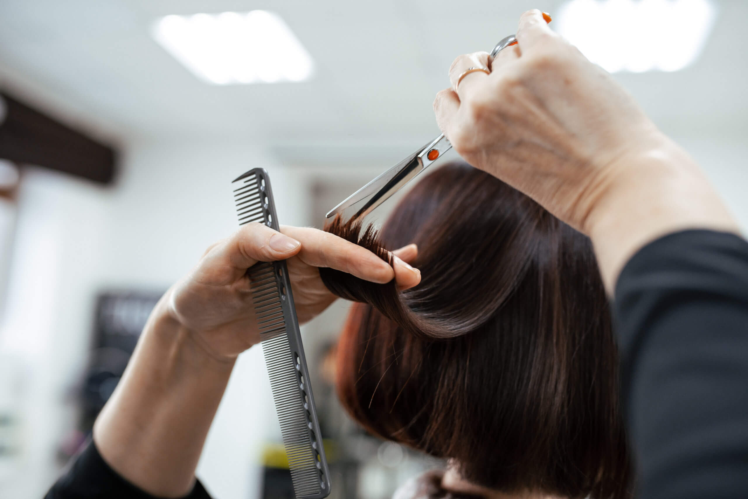 The work of a hairdresser. Hairdresser cut hair of a woman in a beauty salon. Close-up of hands