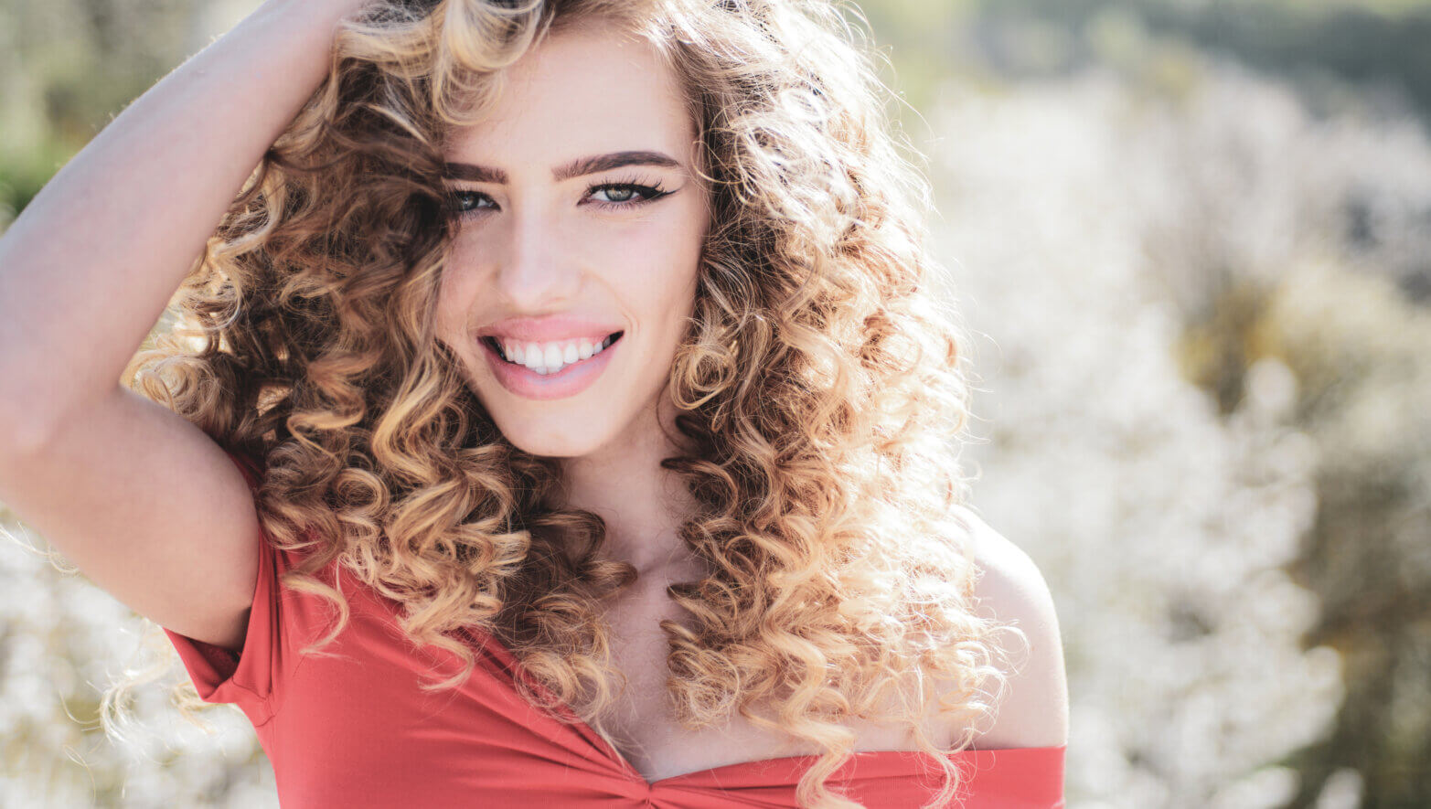 Spring girl with curly hair smiling. Beauty hair Salon. Beauty girl with long and shiny curly hair. Trendy haircuts. Long healthy hair. Spring emotions