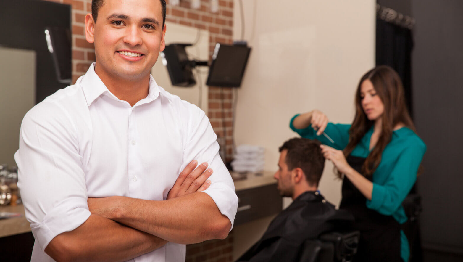 Business owner in his shop. Handsome young barber shop owner smiling and managing his business