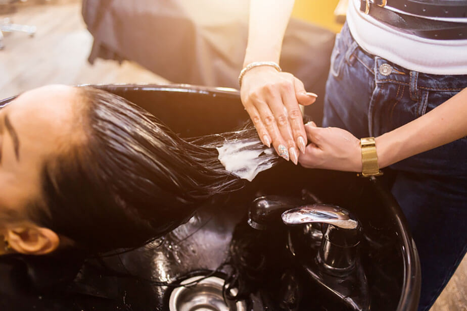 stylist washing client hair in sink