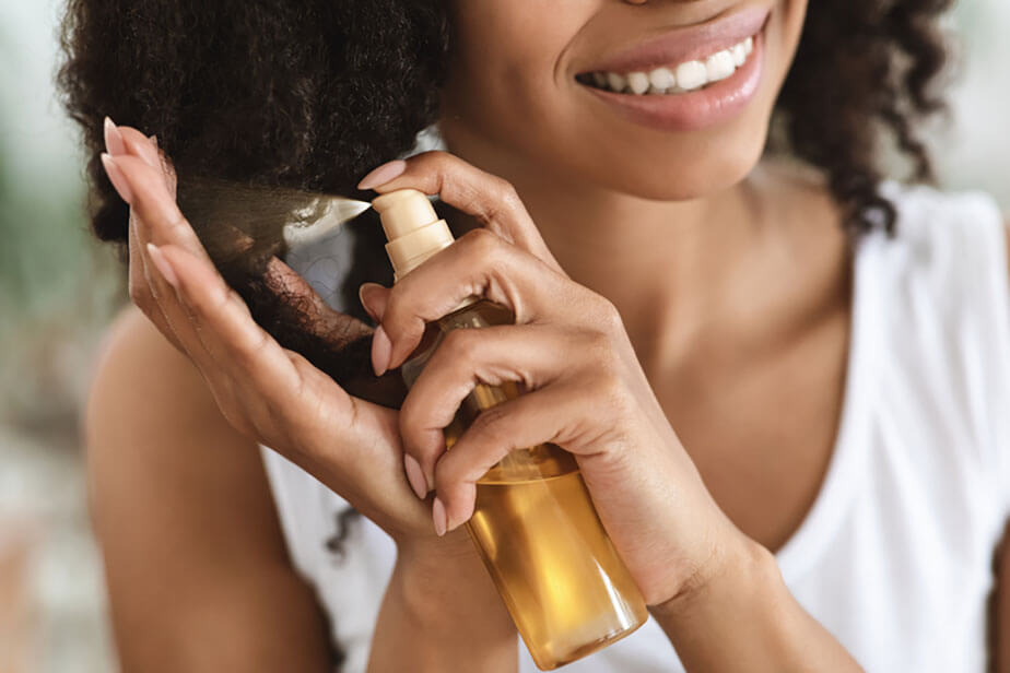 spraying oil onto hair