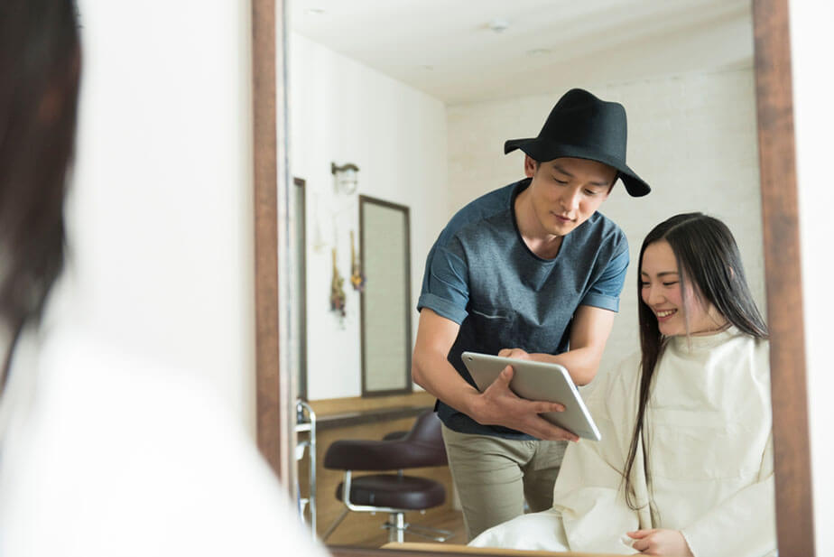 hairdresser consulting with client using tablet